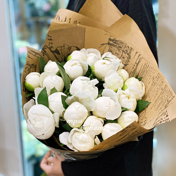 23 белых пиона Дюшес в крафте (в руках флориста)